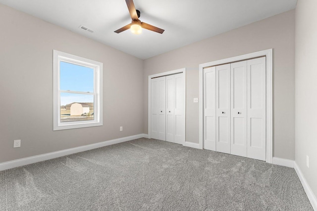 unfurnished bedroom featuring ceiling fan, carpet flooring, and multiple closets