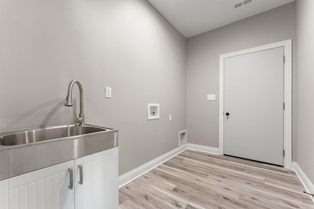 washroom featuring sink, hookup for a washing machine, light hardwood / wood-style floors, and cabinets