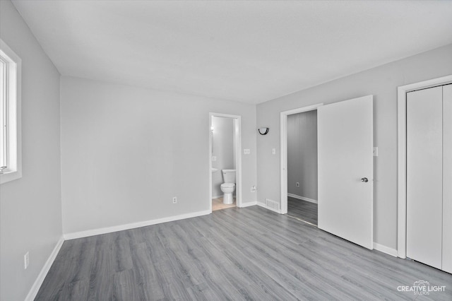 unfurnished bedroom with light hardwood / wood-style flooring and connected bathroom