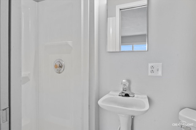 bathroom featuring sink, toilet, and a shower