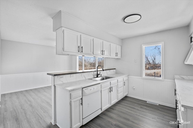 kitchen with white cabinets, dark wood-type flooring, sink, kitchen peninsula, and white dishwasher