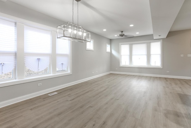 unfurnished dining area featuring light wood-type flooring, ceiling fan, and a wealth of natural light