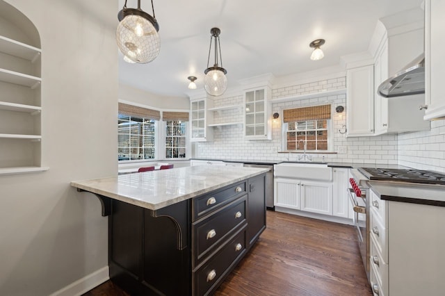 kitchen featuring hanging light fixtures, stainless steel stove, white cabinets, and wall chimney exhaust hood