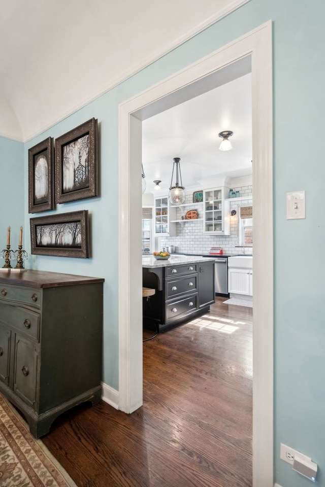 bar with dark wood-type flooring, dishwasher, and backsplash