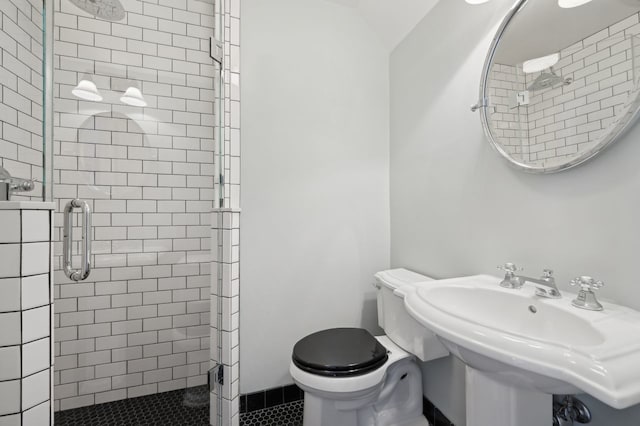 bathroom with toilet, a shower with shower door, and sink