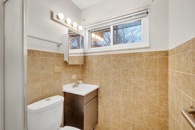 bathroom featuring toilet, vanity, and tile walls