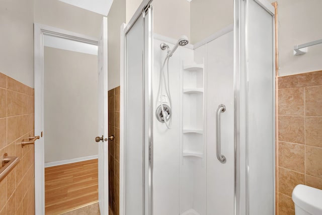 bathroom with tile walls, an enclosed shower, and toilet