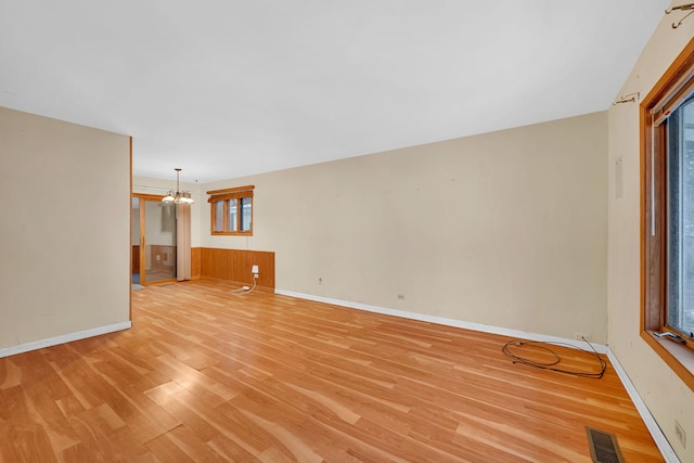 unfurnished living room featuring light wood-type flooring and an inviting chandelier