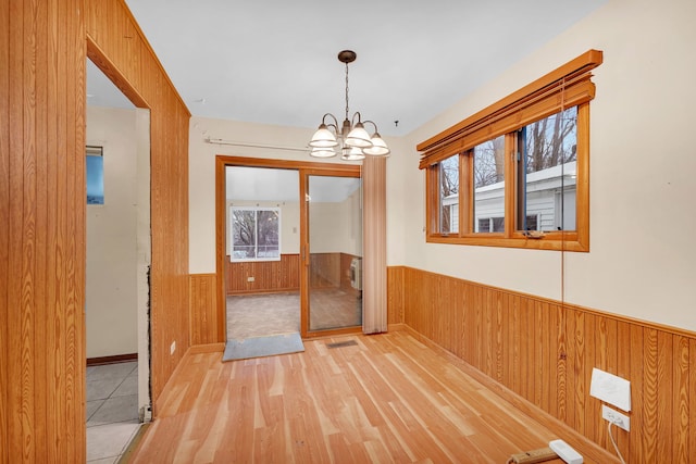 interior space with wood walls, light hardwood / wood-style floors, and a notable chandelier