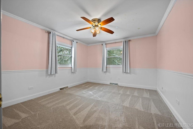 spare room featuring crown molding, a healthy amount of sunlight, and light colored carpet