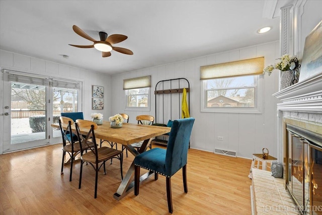 dining room with ceiling fan, a fireplace, and light hardwood / wood-style flooring