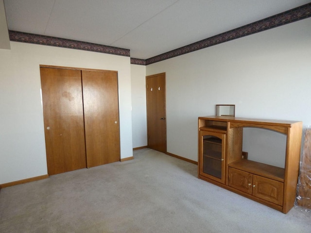 unfurnished bedroom with light colored carpet and a closet