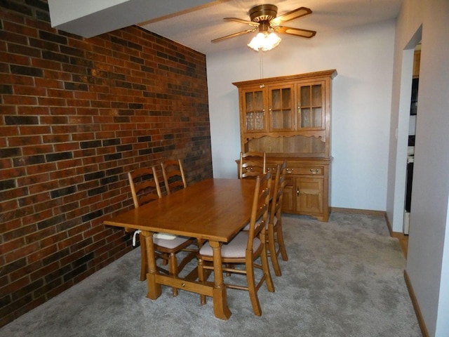 dining room with ceiling fan, light colored carpet, and brick wall