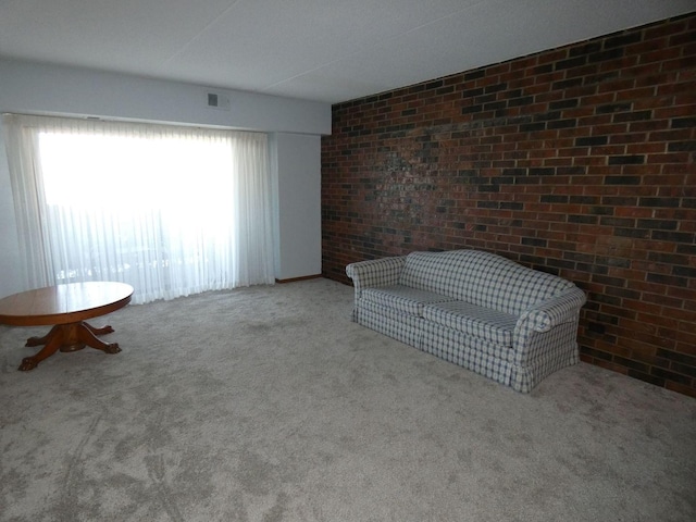 unfurnished room featuring brick wall and light carpet