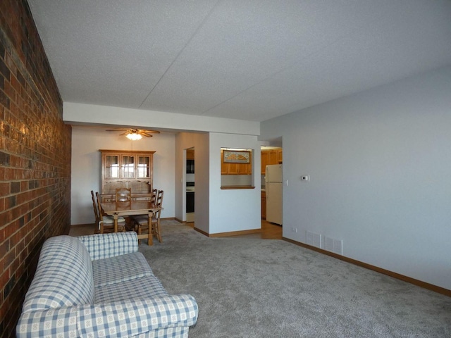 unfurnished living room featuring ceiling fan, brick wall, carpet, and a textured ceiling