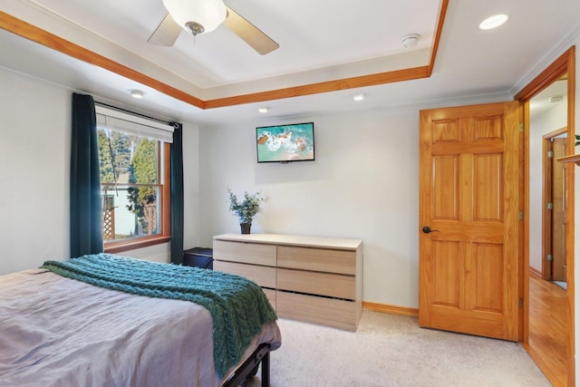 bedroom featuring ceiling fan, ornamental molding, a tray ceiling, and light colored carpet