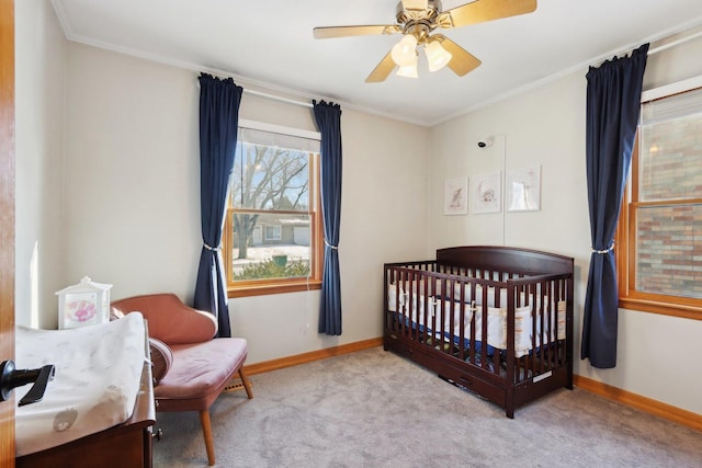 carpeted bedroom with crown molding, a nursery area, and ceiling fan