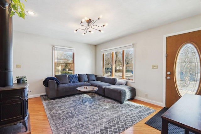 living room with hardwood / wood-style floors, a notable chandelier, and a wood stove