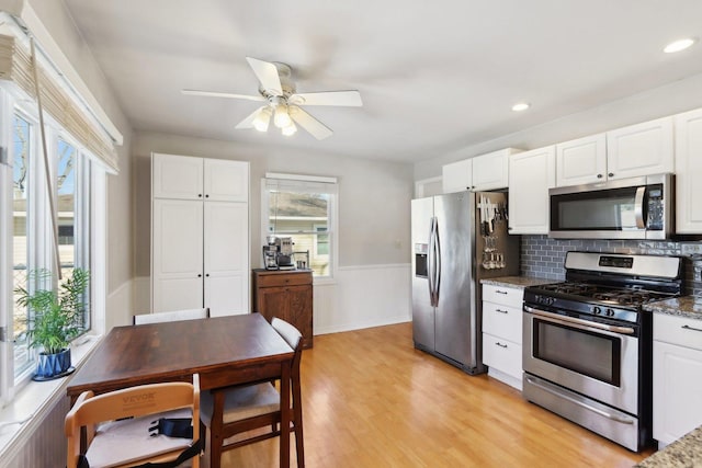 kitchen featuring white cabinetry, appliances with stainless steel finishes, a healthy amount of sunlight, and dark stone countertops