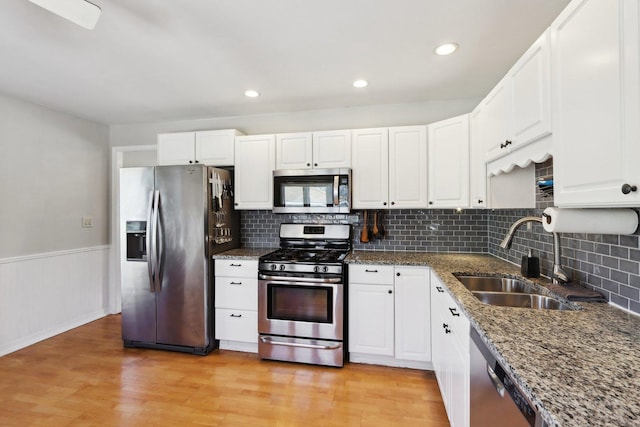 kitchen featuring white cabinetry, appliances with stainless steel finishes, sink, and dark stone counters