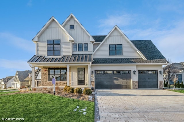 view of front of property featuring covered porch, a garage, and a front lawn