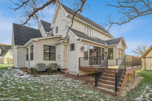 snow covered back of property with central AC, a yard, and a sunroom