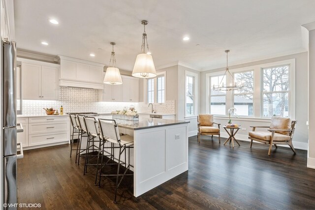 kitchen featuring white cabinets, appliances with stainless steel finishes, a center island, decorative light fixtures, and dark hardwood / wood-style floors