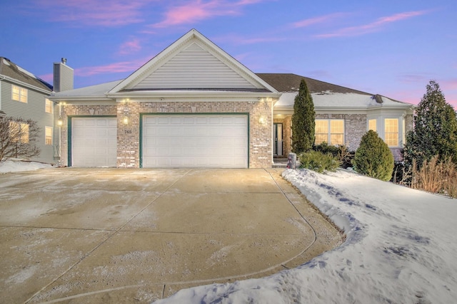 single story home featuring concrete driveway, brick siding, and an attached garage