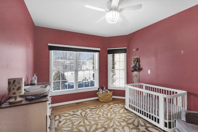 bedroom with ceiling fan, wood finished floors, visible vents, and baseboards