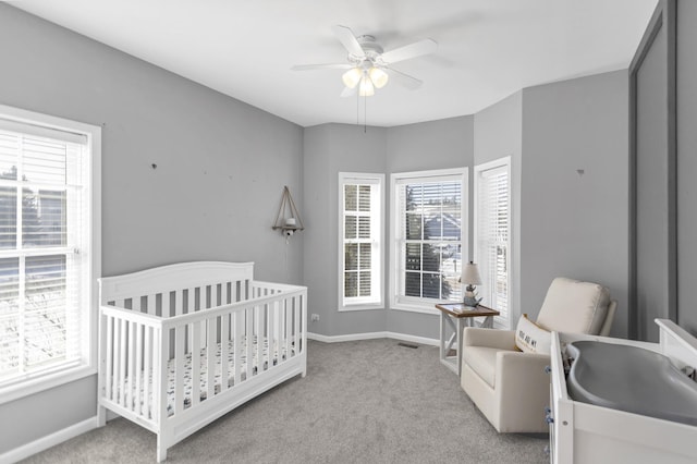 bedroom with light carpet, a nursery area, visible vents, and baseboards