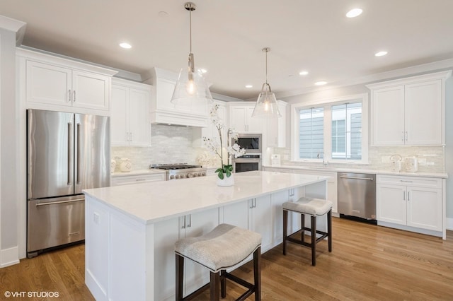 kitchen featuring a center island, white cabinetry, light hardwood / wood-style flooring, stainless steel appliances, and a breakfast bar area