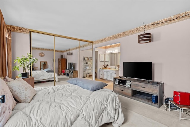 bedroom with ensuite bathroom, carpet flooring, and a closet