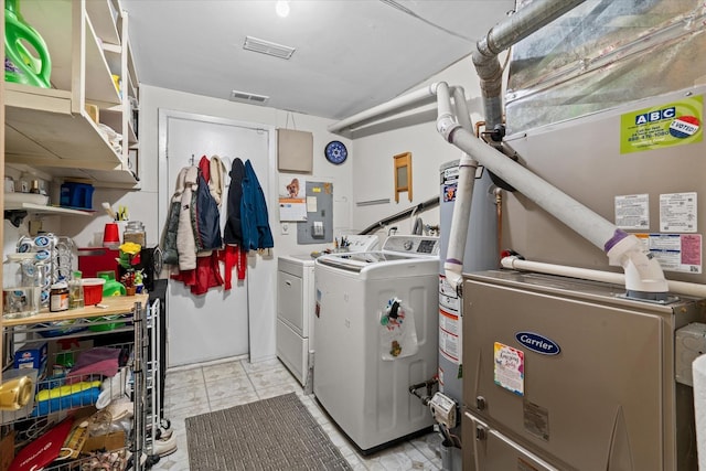 clothes washing area featuring heating unit, washing machine and dryer, and electric panel