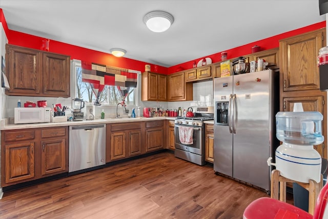 kitchen featuring sink, decorative backsplash, dark wood-type flooring, and appliances with stainless steel finishes