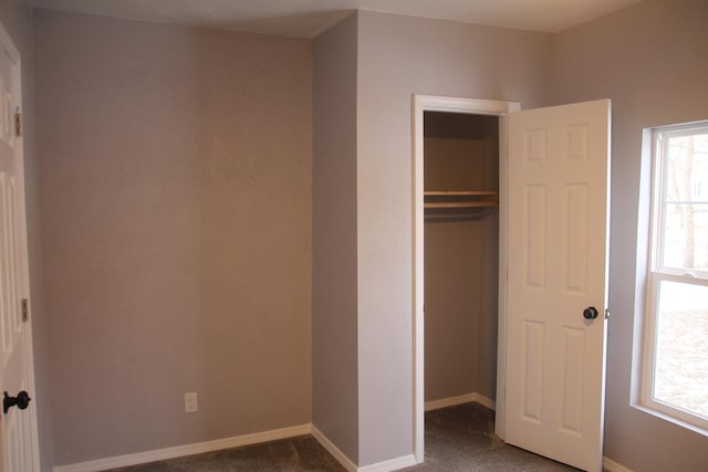 unfurnished bedroom featuring dark carpet and a closet