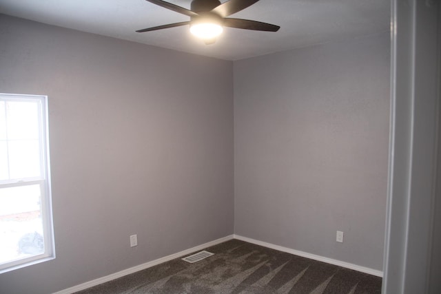 spare room with ceiling fan and dark carpet