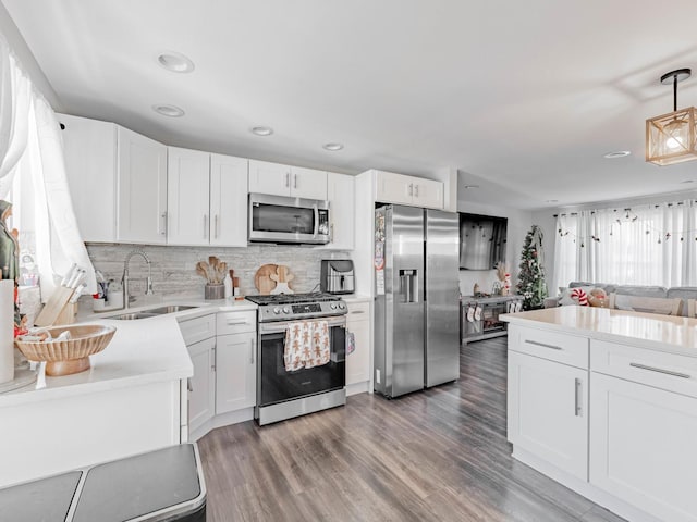 kitchen featuring white cabinetry, stainless steel appliances, and hanging light fixtures