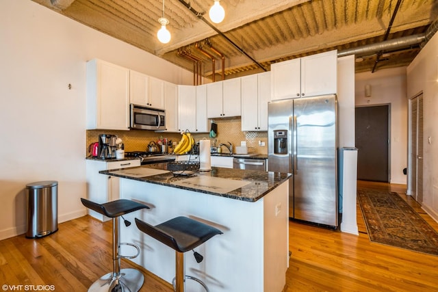 kitchen with a kitchen island, tasteful backsplash, white cabinets, hanging light fixtures, and stainless steel appliances