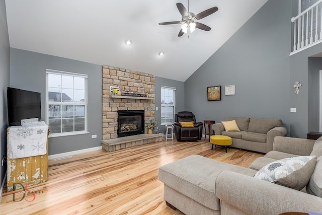 living room with ceiling fan, high vaulted ceiling, a fireplace, and light hardwood / wood-style flooring