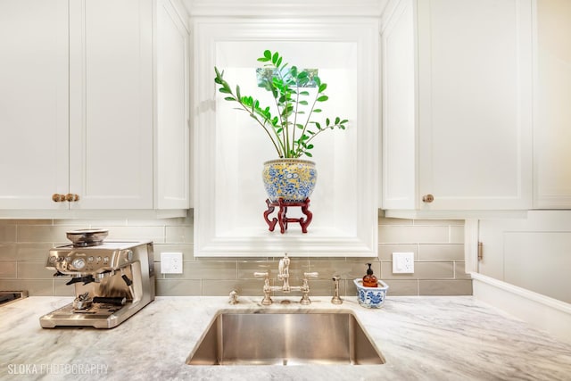 kitchen with sink, white cabinets, light stone counters, and decorative backsplash