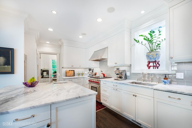 kitchen with white cabinetry, stainless steel range, sink, and wall chimney range hood