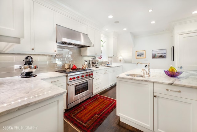 kitchen with luxury range, light stone countertops, white cabinets, and wall chimney exhaust hood