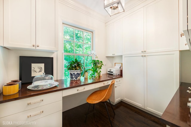 home office with crown molding, dark hardwood / wood-style floors, and built in desk