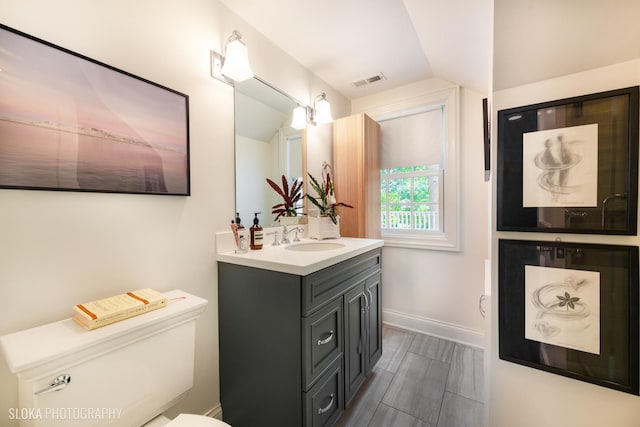 bathroom with vanity, vaulted ceiling, and toilet