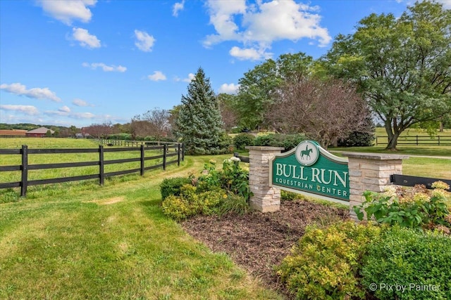 community / neighborhood sign featuring a lawn and a rural view