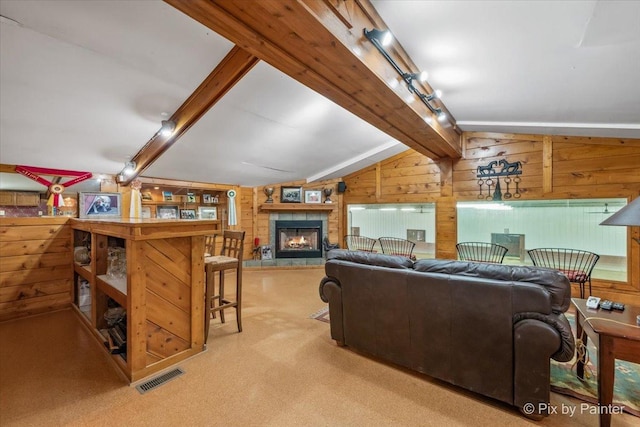 living room featuring a fireplace, wooden walls, track lighting, light colored carpet, and lofted ceiling with beams