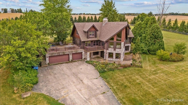 view of front of house with a garage, a balcony, a front lawn, and a rural view