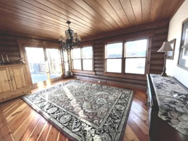 sitting room with dark wood-type flooring, a chandelier, and rustic walls