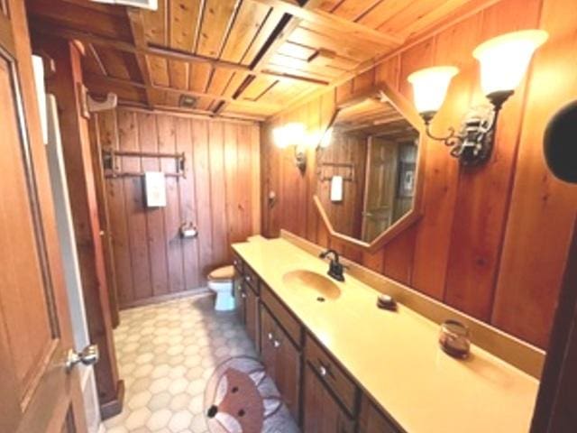 bathroom with toilet, wood walls, and wooden ceiling