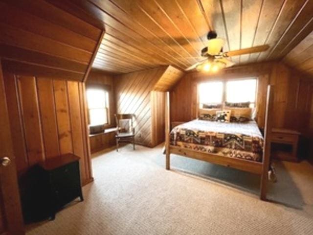 bedroom featuring light carpet, wooden walls, vaulted ceiling, ceiling fan, and wooden ceiling